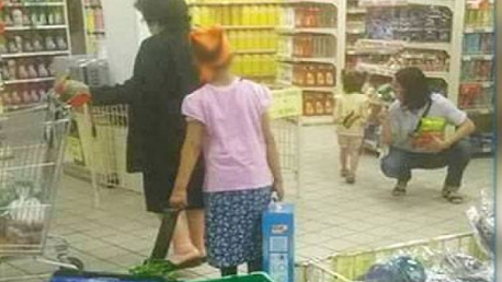 صورة لطفلة ترافق إمراة تستغلها في حمل أكياس ثقيلة